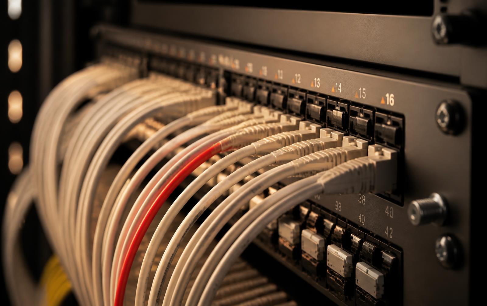 Network patch panel with neatly routed cables, one red cable standing out among ivory cables